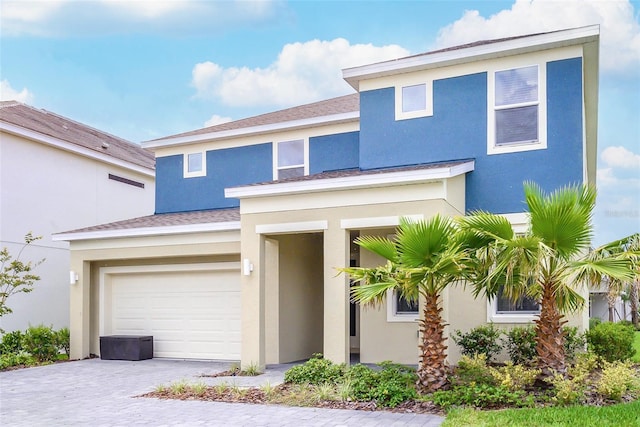 view of front facade with a garage, decorative driveway, and stucco siding