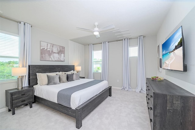 bedroom with a ceiling fan, light colored carpet, and baseboards