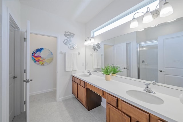 bathroom featuring double vanity, a stall shower, a sink, and baseboards