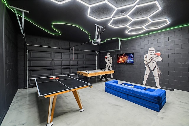 playroom with a garage, finished concrete floors, and concrete block wall