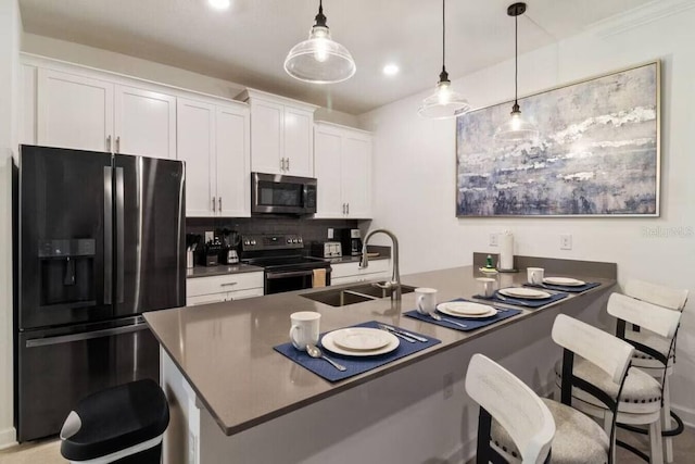 kitchen with decorative backsplash, appliances with stainless steel finishes, white cabinets, sink, and decorative light fixtures