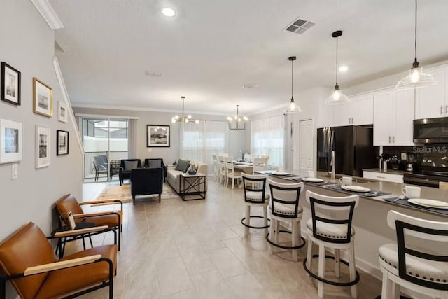 kitchen with white cabinets, black fridge, a kitchen bar, an inviting chandelier, and electric range