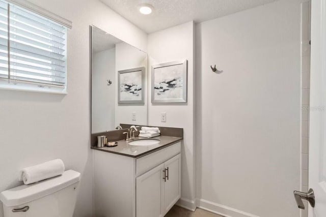 bathroom featuring a textured ceiling, toilet, and vanity