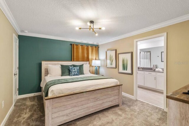 carpeted bedroom featuring ensuite bath, ornamental molding, and a textured ceiling