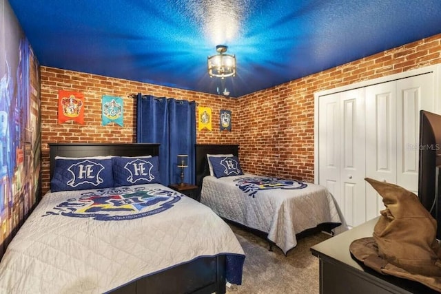 carpeted bedroom featuring a closet and brick wall