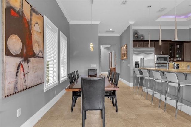 tiled dining room with ornamental molding and sink