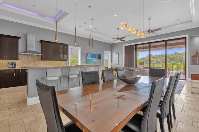 tiled dining space featuring ceiling fan, a healthy amount of sunlight, and a tray ceiling