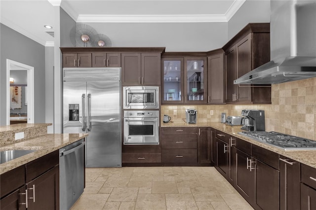 kitchen with tasteful backsplash, built in appliances, wall chimney range hood, and light stone countertops