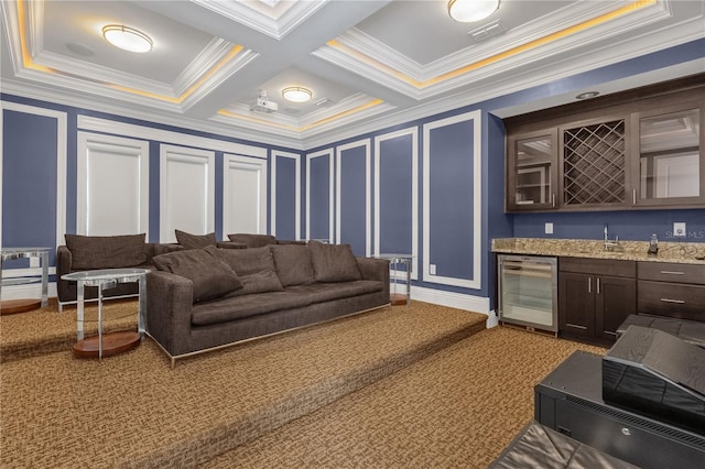 carpeted cinema room with crown molding, indoor wet bar, wine cooler, coffered ceiling, and beamed ceiling