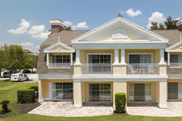 rear view of property featuring a lawn and a balcony