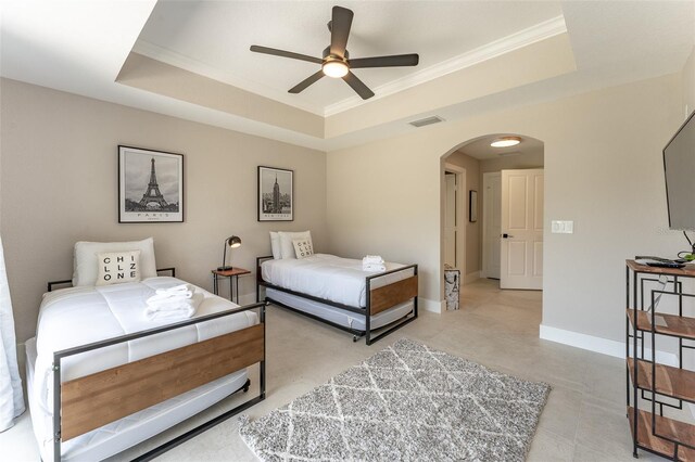 bedroom featuring ceiling fan, a tray ceiling, light tile patterned floors, and ornamental molding