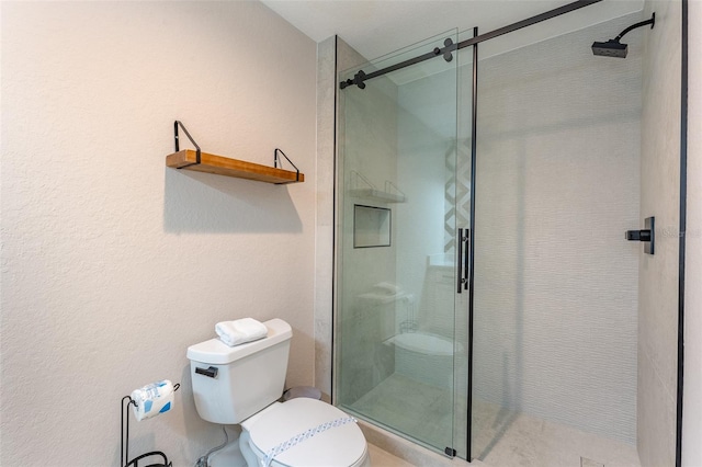 bathroom featuring a shower with shower door and toilet