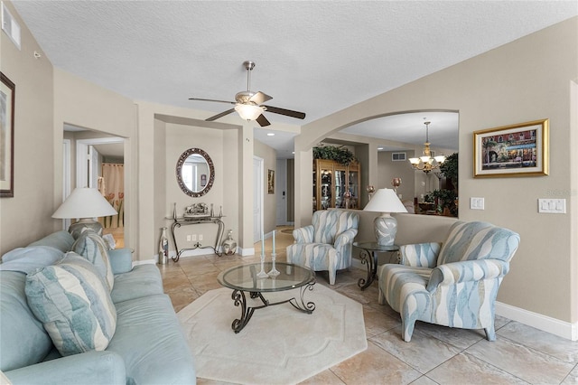 tiled living room with ceiling fan with notable chandelier and a textured ceiling