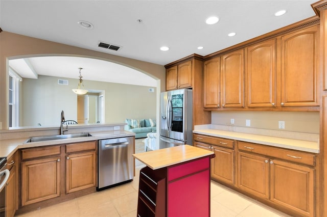 kitchen featuring hanging light fixtures, stainless steel appliances, wood counters, light tile patterned floors, and sink