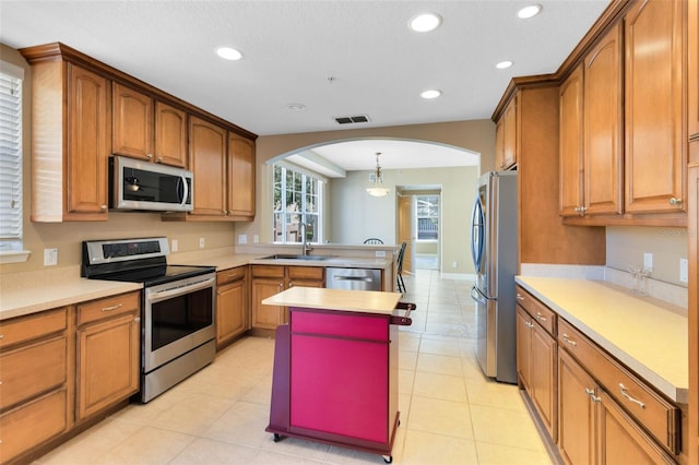 kitchen with stainless steel appliances, a center island, sink, light tile patterned floors, and pendant lighting