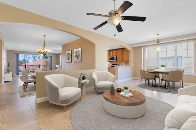 living room featuring ceiling fan with notable chandelier and light tile patterned floors