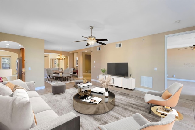 tiled living room featuring ceiling fan with notable chandelier