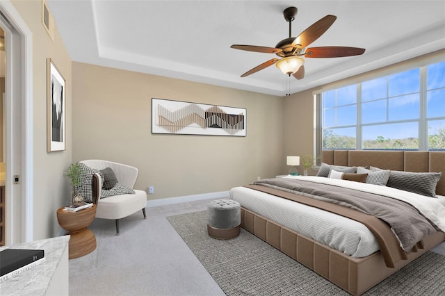 bedroom featuring a raised ceiling, carpet, and ceiling fan