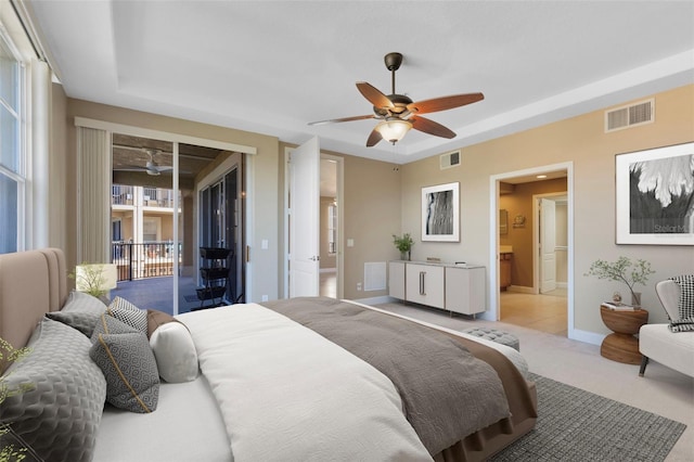 bedroom with access to outside, ensuite bath, ceiling fan, a raised ceiling, and light colored carpet