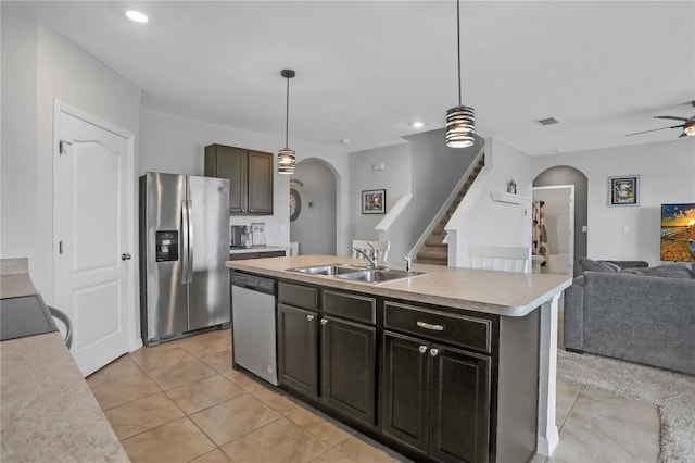 kitchen with an island with sink, hanging light fixtures, stainless steel appliances, sink, and ceiling fan