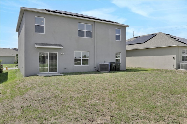 rear view of property with solar panels, a lawn, and central AC