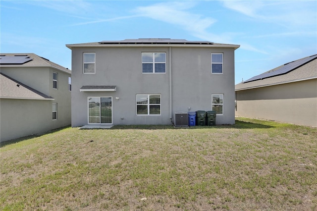 rear view of property with a yard, solar panels, and central AC