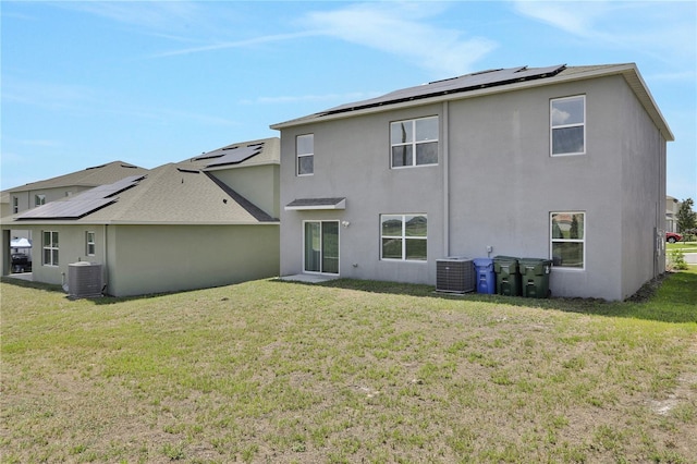 rear view of property with central AC unit and a yard