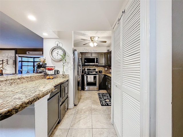 kitchen with light tile patterned flooring, tasteful backsplash, appliances with stainless steel finishes, ceiling fan, and light stone countertops