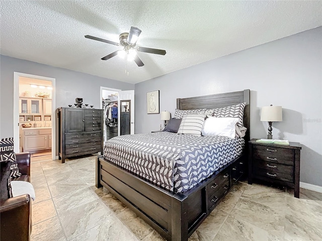 bedroom with a textured ceiling, a walk in closet, a closet, and ceiling fan