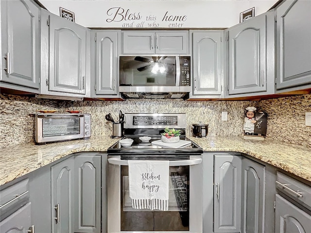 kitchen featuring stainless steel appliances, tasteful backsplash, gray cabinets, and light stone counters