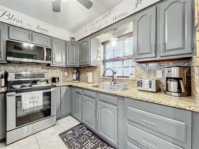 kitchen with sink, light tile patterned floors, gray cabinets, and appliances with stainless steel finishes