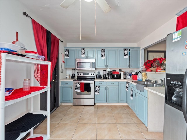 kitchen featuring ceiling fan, blue cabinets, light tile patterned flooring, sink, and stainless steel appliances