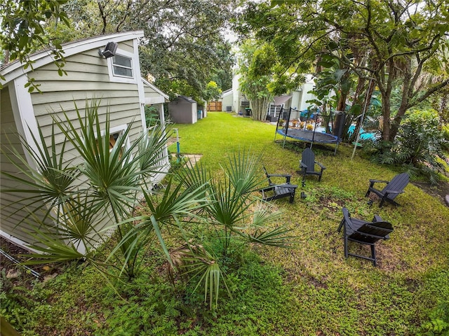 view of yard with a trampoline and an outdoor fire pit