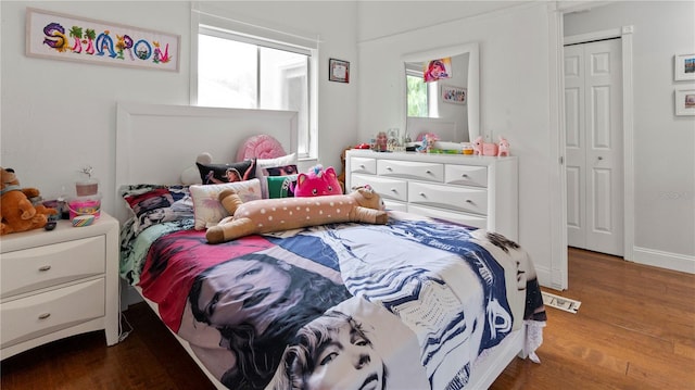 bedroom with dark wood-type flooring and a closet