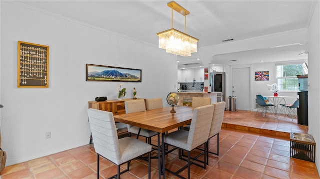 tiled dining space featuring a notable chandelier and crown molding