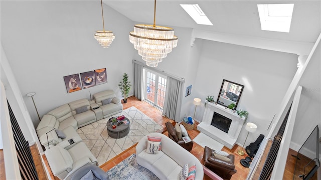 living room featuring a fireplace, high vaulted ceiling, a notable chandelier, a skylight, and wood-type flooring