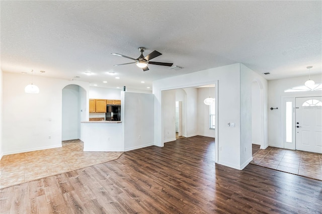 unfurnished living room featuring ceiling fan, hardwood / wood-style flooring, and a textured ceiling