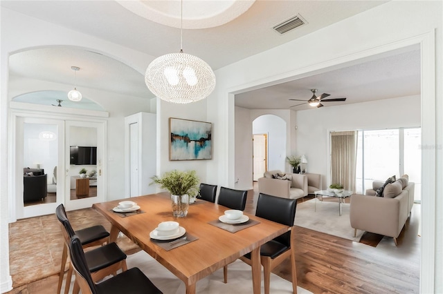 dining space featuring ceiling fan with notable chandelier and wood-type flooring