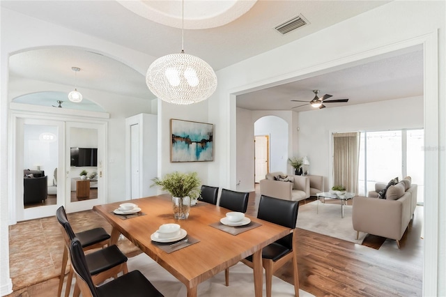 dining area featuring visible vents, arched walkways, a ceiling fan, and wood finished floors