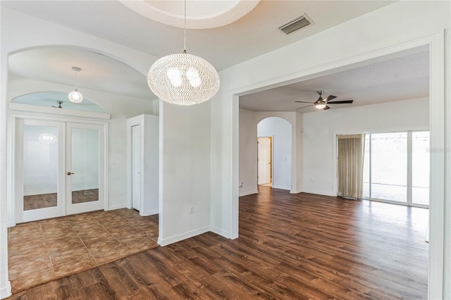 spare room featuring french doors, hardwood / wood-style flooring, and ceiling fan with notable chandelier