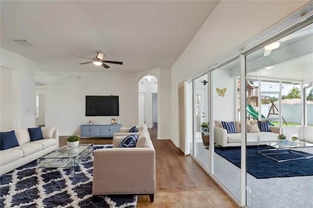 living area with arched walkways, ceiling fan, light tile patterned floors, and visible vents