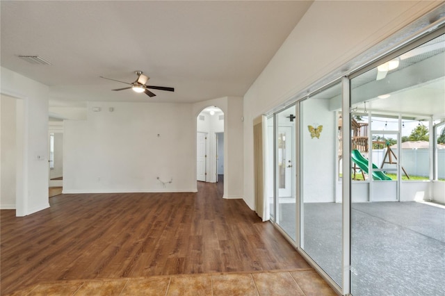 unfurnished room with baseboards, visible vents, arched walkways, ceiling fan, and wood finished floors