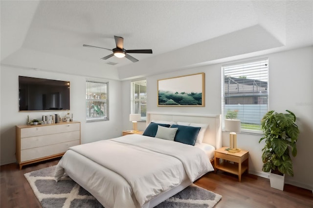 bedroom with hardwood / wood-style floors, a tray ceiling, and ceiling fan