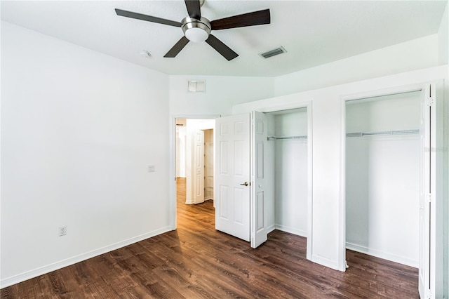 unfurnished bedroom featuring dark wood-style floors, two closets, visible vents, and baseboards