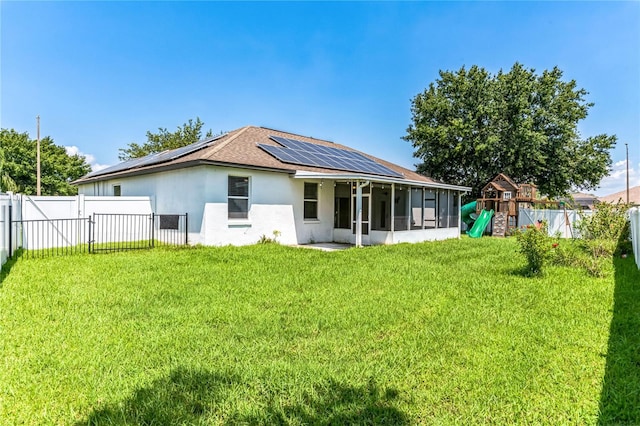 rear view of property with a sunroom, a playground, a lawn, and a fenced backyard