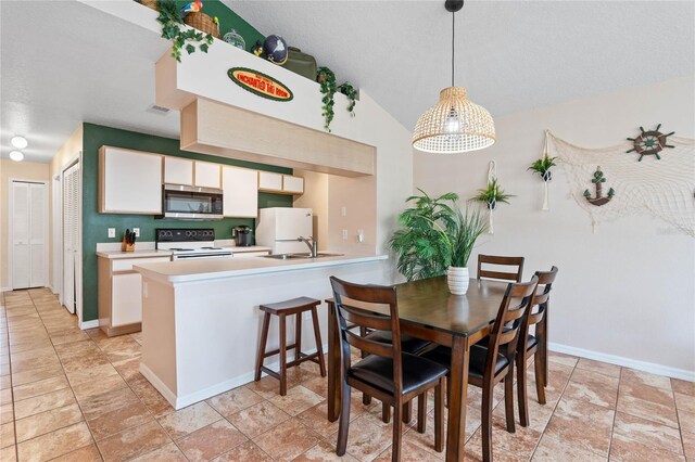 dining room with sink, vaulted ceiling, and light tile patterned flooring