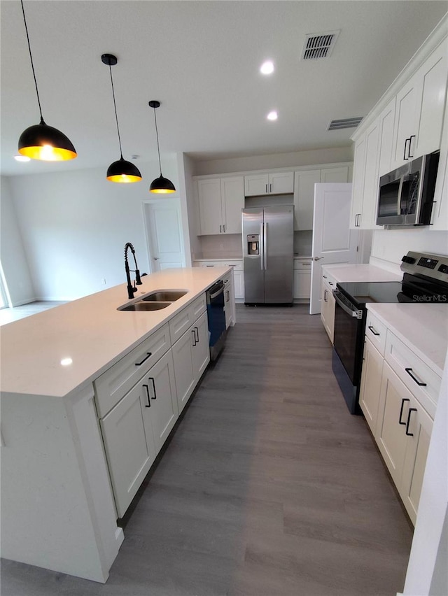 kitchen featuring appliances with stainless steel finishes, sink, white cabinets, pendant lighting, and dark hardwood / wood-style flooring