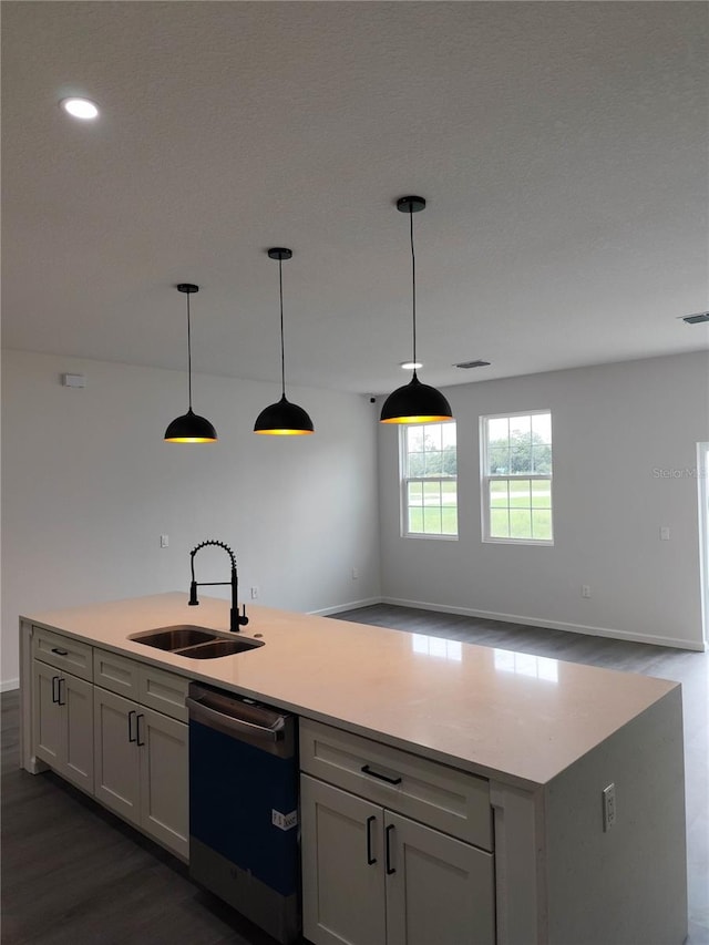 kitchen featuring dark wood-type flooring, dishwashing machine, a center island with sink, and sink