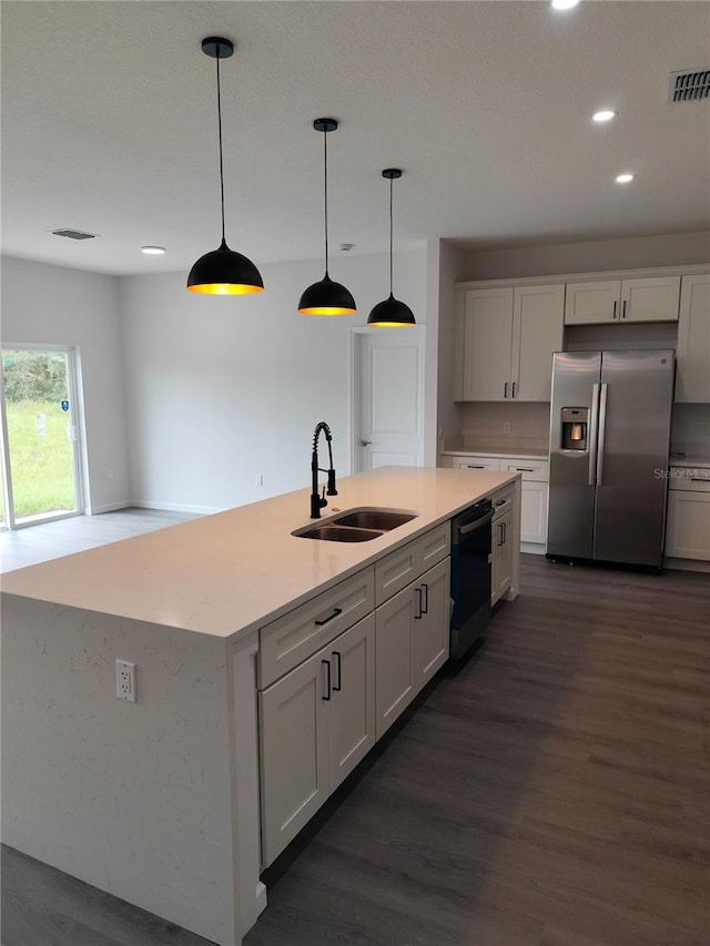 kitchen featuring pendant lighting, dark hardwood / wood-style floors, stainless steel fridge with ice dispenser, dishwasher, and sink