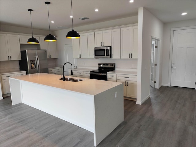 kitchen featuring appliances with stainless steel finishes, dark wood-type flooring, an island with sink, and sink